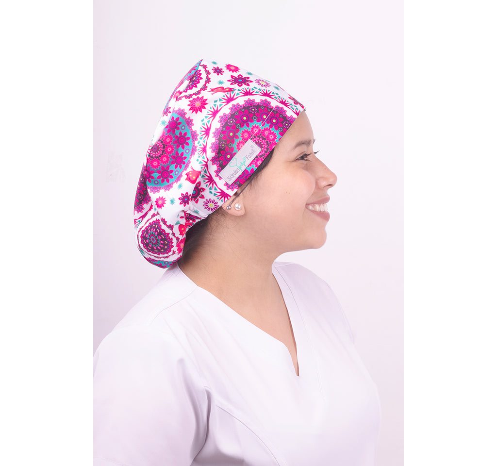 Una mujer usando un gorro quirúrgico con una horma elástica. Tiene un estampado de mandalas rosadas sobre un fondo blanco.